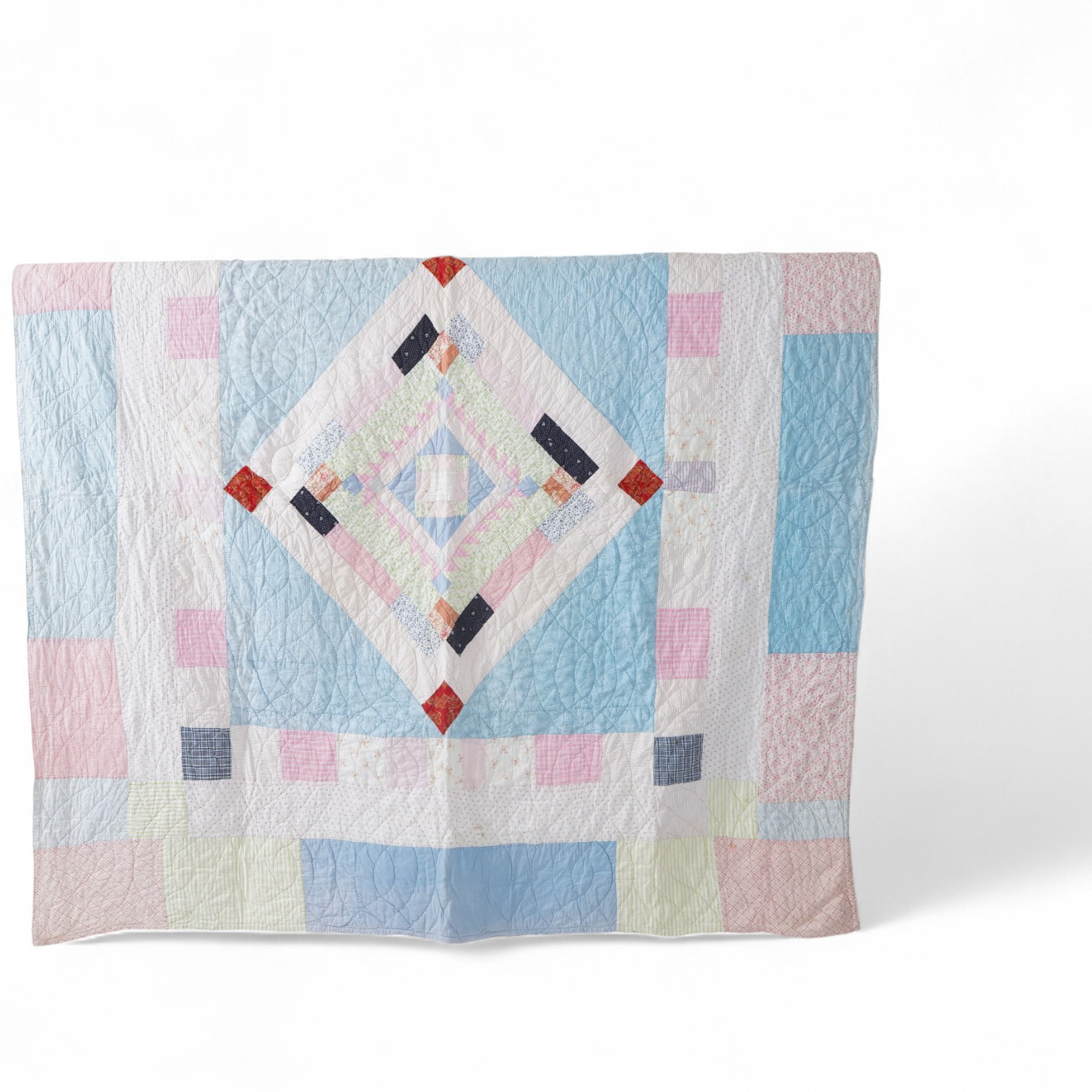A 1900-1910 English, possibly north country hand quilted bedcover. Designed with a large central medallion, hand quilted using mostly pastel patterned and plain cottons and feature red and black cottons as highlights, ba
